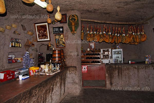 Die H&ouml;hlenbar wirkt durch ihr dunkles Innere und die zahlreichen Schinken, die von der Decke h&auml;ngen, sehr rustikal.