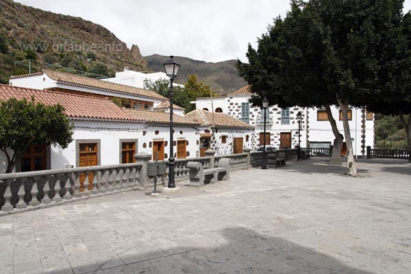 Der Platz um die Kirche von Santa Lucia wird von schattenspendenden B&auml;umen und netten kleinen H&auml;uschen umrahmt.