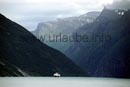 Von Bord der Autofähre Hellesylt-Geiranger geht der Blick in den Sunnylfsfjord. Dort nähert sich von Alesund kommend, im Schatten von über 1500 Meter hohen Bergen, die Hurtigrute MS Nordlys auf ihrem Weg nach Geiranger.